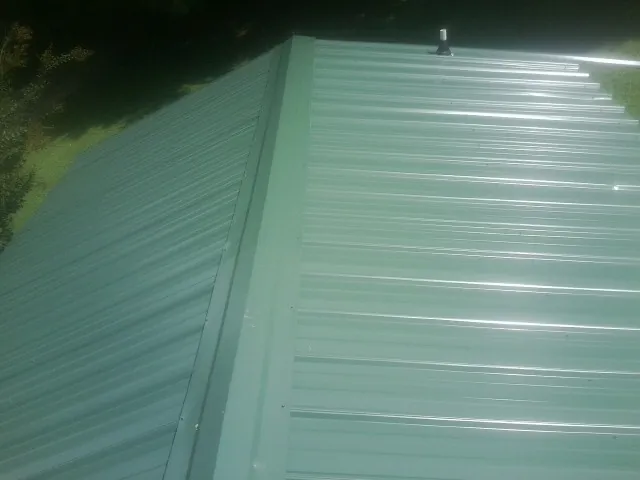 New green metal panels meeting at the ridge of a roof — Flat Roof Repair work by our crew in Grantsville