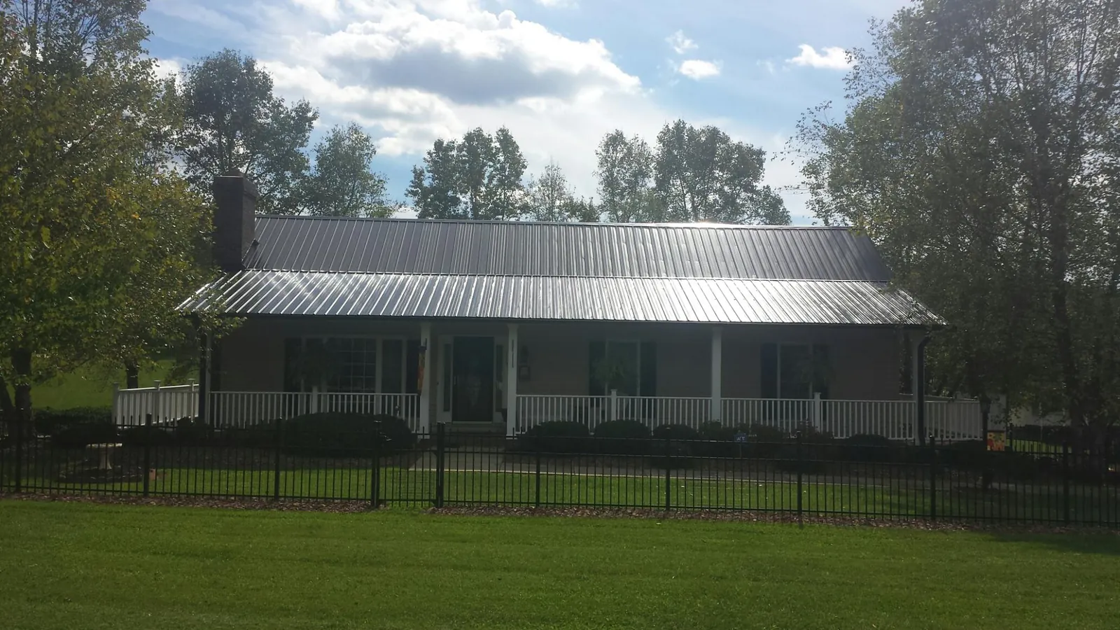 Gray metal roof on a brick ranch with a full width front porch — Gutter Guard Installation work by our crew in Grantsville
