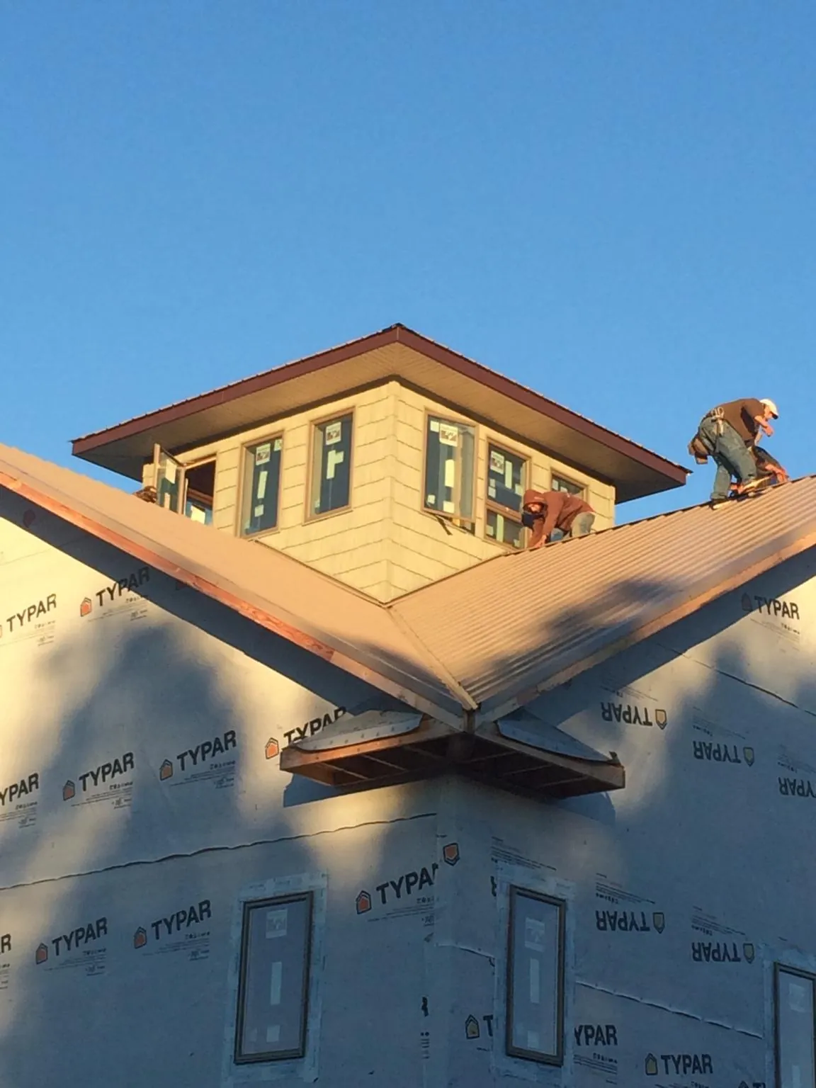 Roofers working around a rooftop cupola on a new metal roof at sunset — Roof Waterproofing in Grantsville by Roofing Brothers
